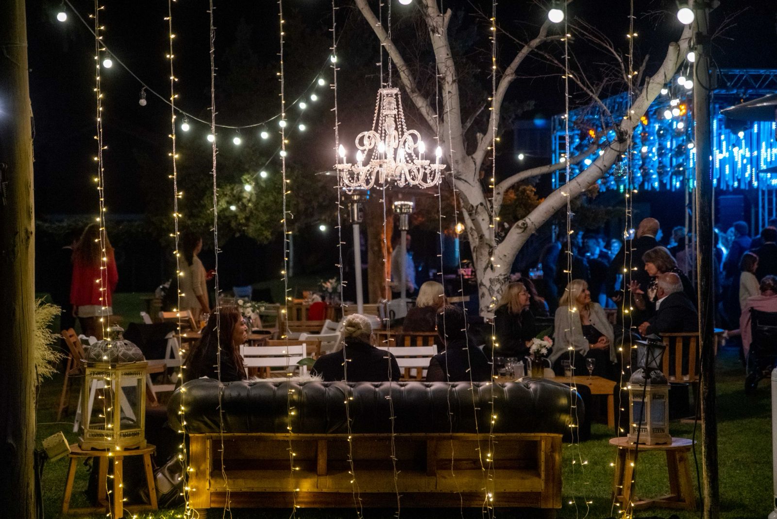 Jardín iluminado de noche con candelabro y luces colgantes