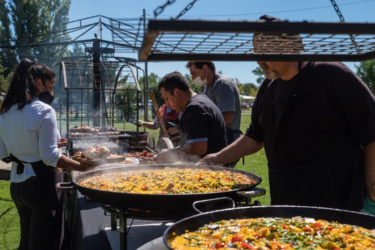 Servicio de catering preparando paella en grandes paelleras durante un evento al aire libre