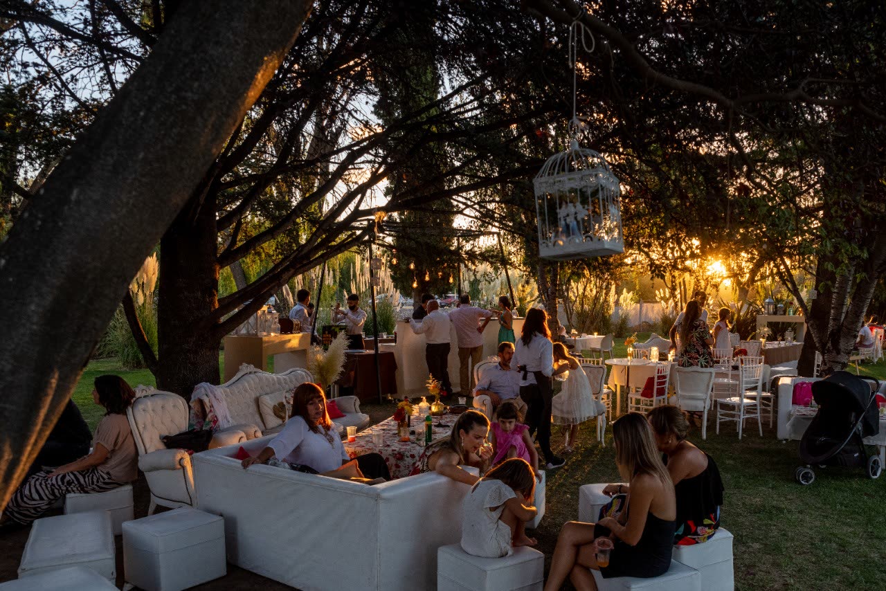 Invitados reunidos entre los árboles del predio de Las Cortaderas al atardecer