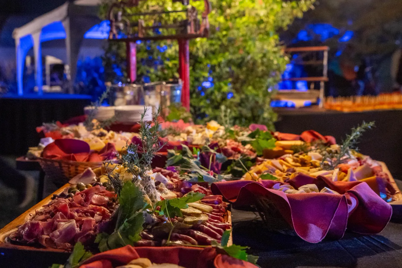 Mesa de catering con tablas de fiambres, quesos y bocados en un evento nocturno