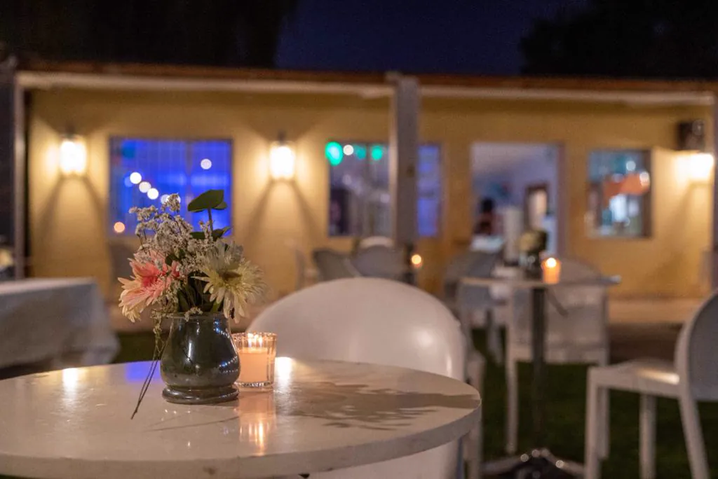Mesa alta con flores y velas frente a las instalaciones iluminadas de noche
