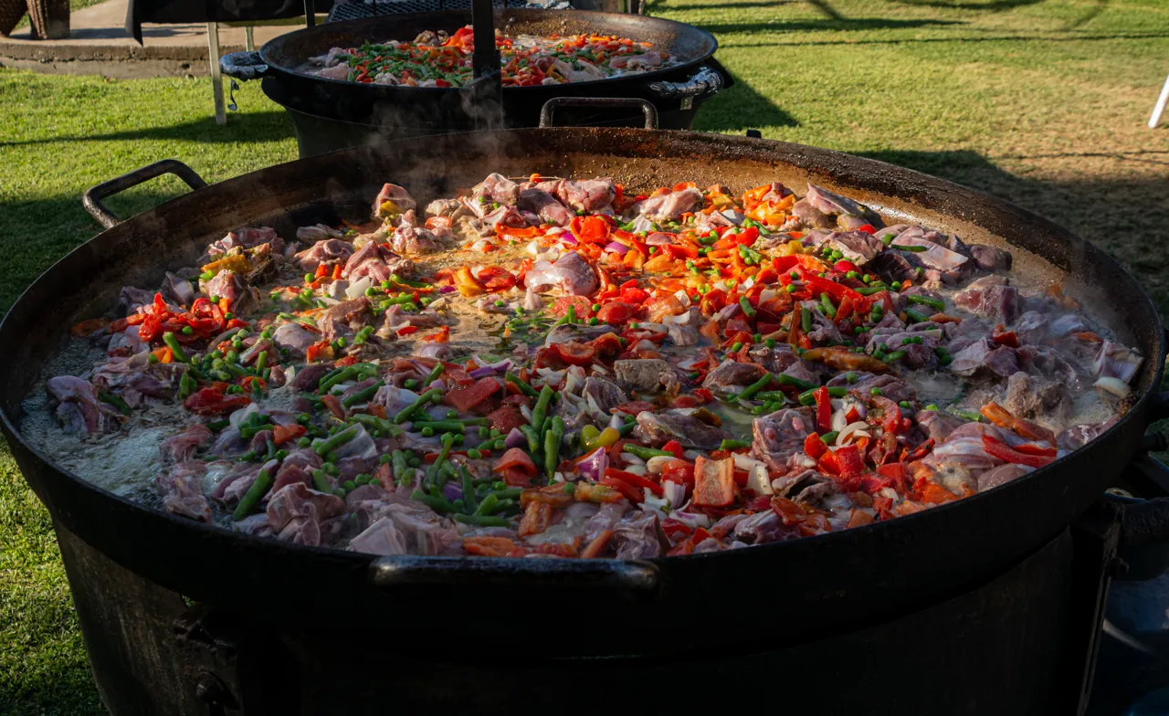 Disco gigante con guiso de carne y vegetales cocinándose al aire libre