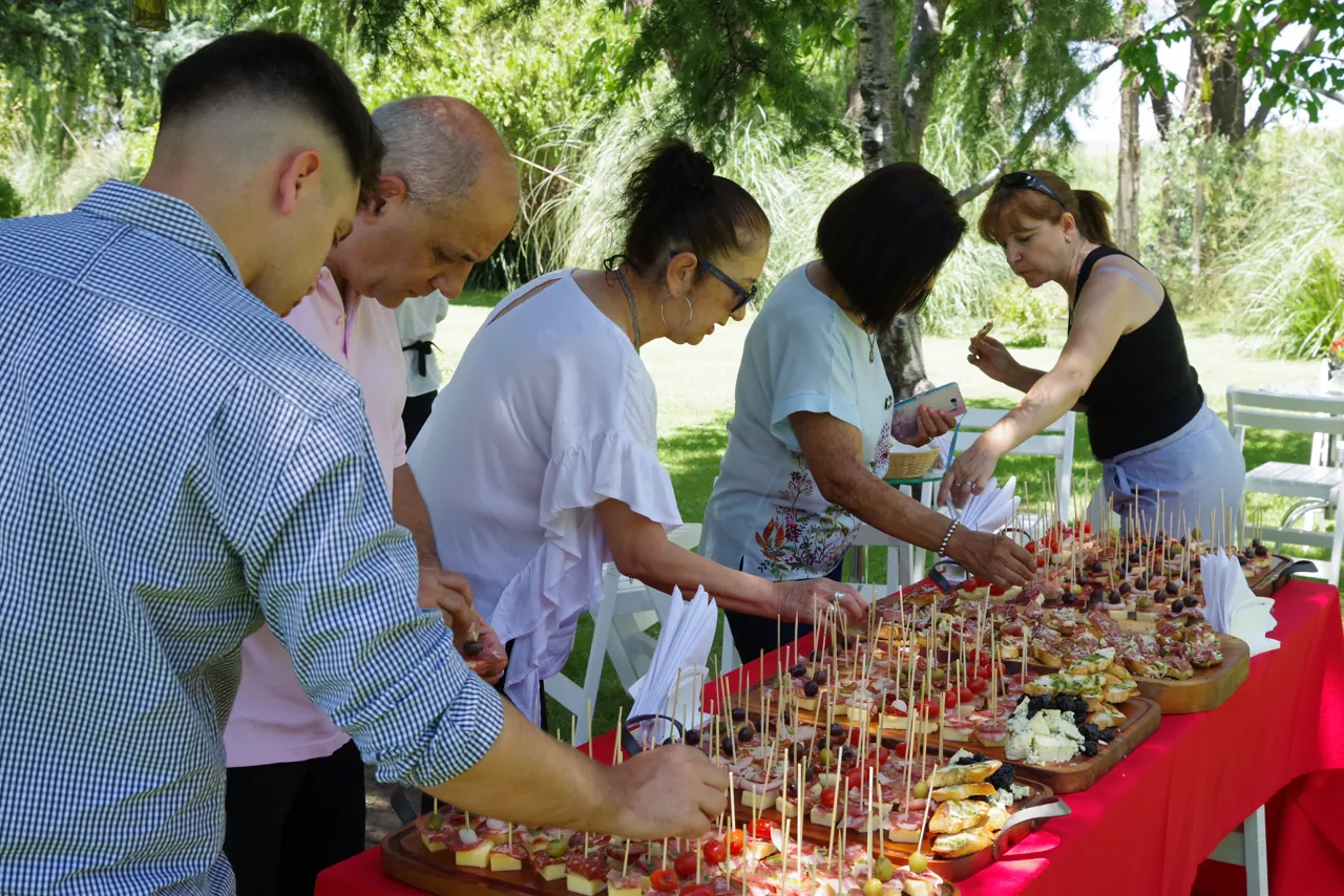 Invitados sirviéndose de la mesa de pinchos al aire libre