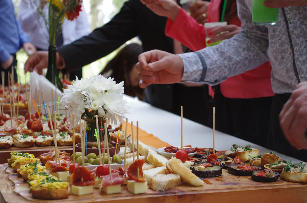 Invitados eligiendo canapés de la mesa de recepción