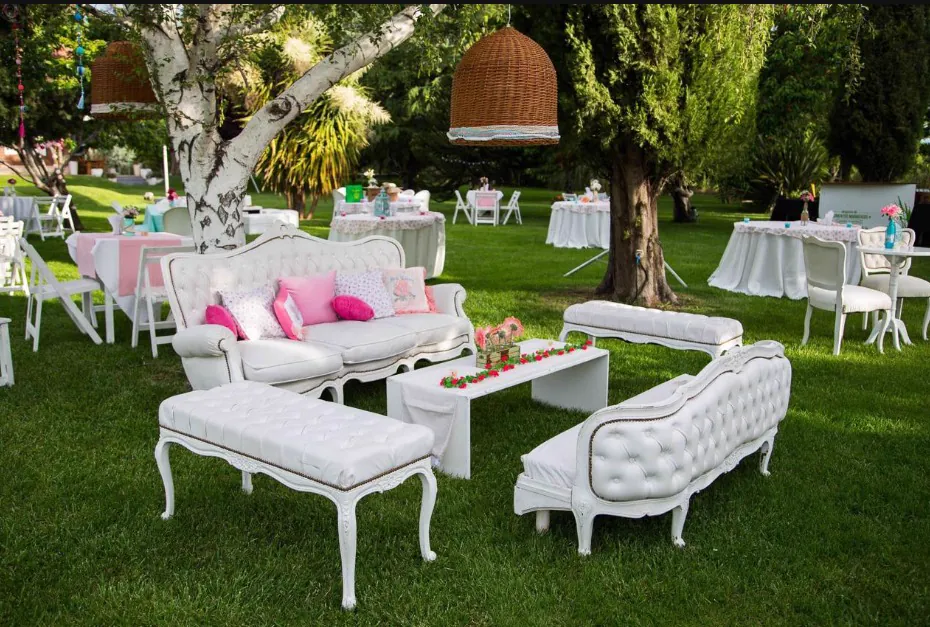 Living de sillones blancos con almohadones rosas en el parque