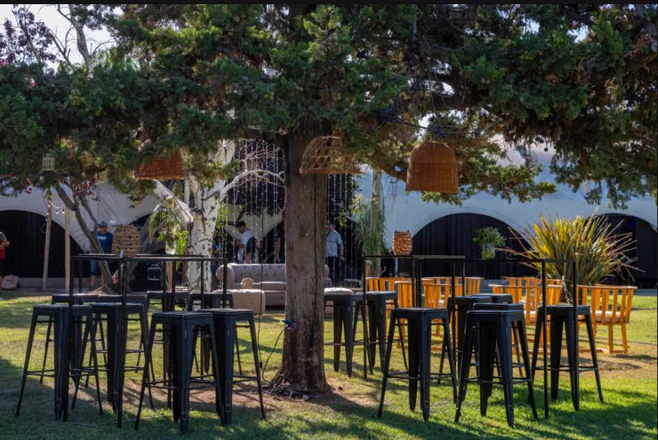 Mesas altas con lámparas de mimbre colgadas del árbol en el jardín