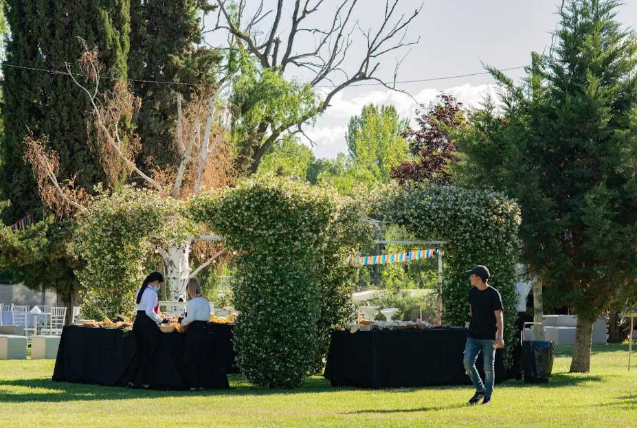 Arcos de verde con mesas de servicio en el jardín del predio