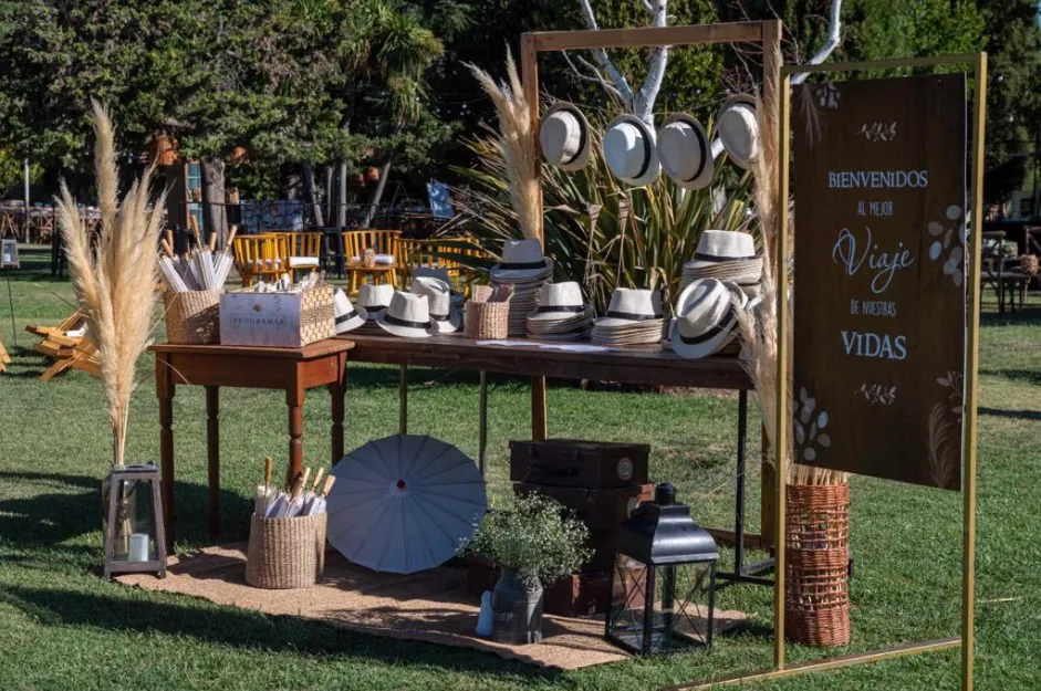 Mesa de bienvenida con sombreros y cartel de bienvenida en el jardín