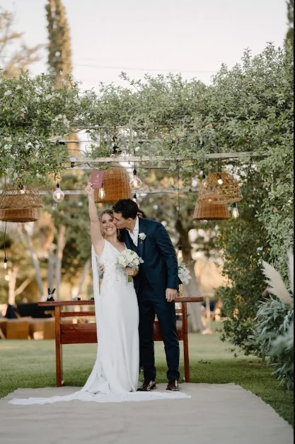 Los novios brindando bajo la pérgola del jardín