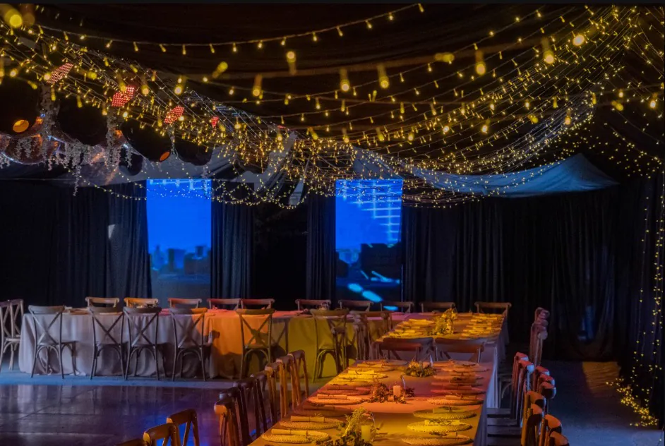 El salón vestido de noche con guirnaldas de luces sobre los tablones