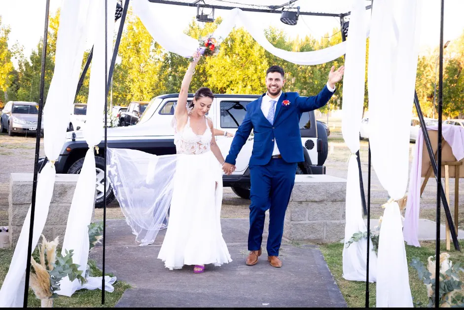 Los novios festejando su entrada bajo el gazebo de telas blancas