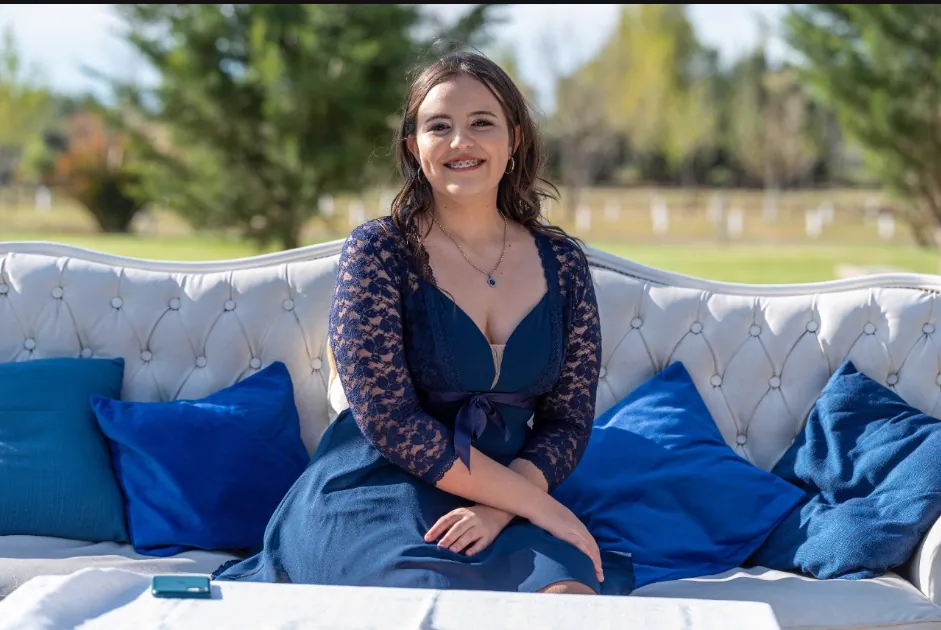 Invitada sonriendo en el sillón capitoné con almohadones azules del jardín