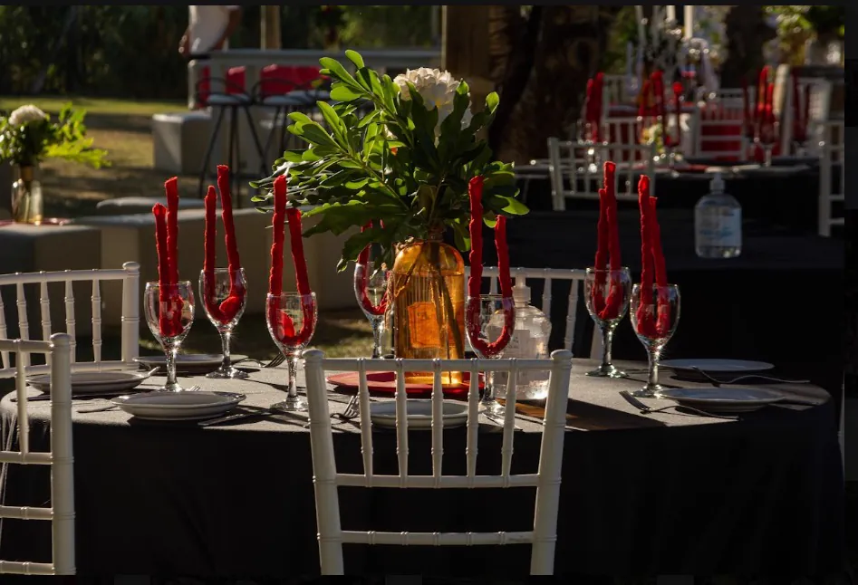 Mesa vestida de negro con copas y servilletas rojas para un evento corporativo