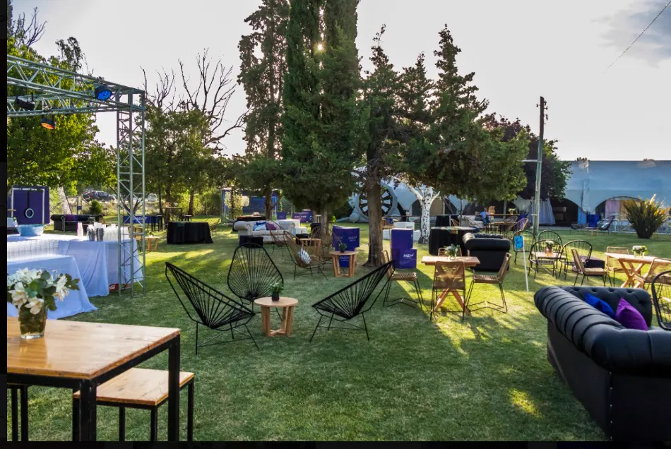 Livings y mesas altas montados en el jardín frente al escenario