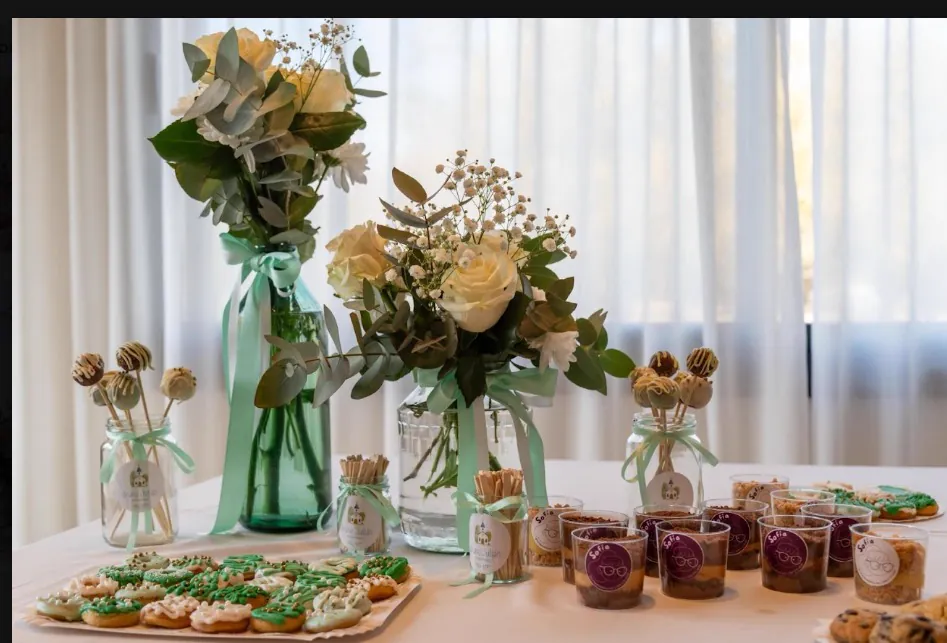 Mesa dulce decorada con flores, cookies y vasitos de postre