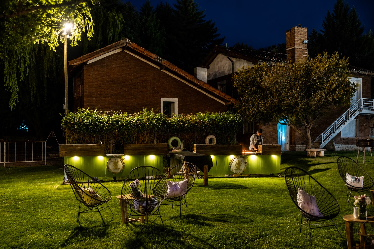 Barra de catering iluminada de noche en el parque, con livings de sillas Acapulco