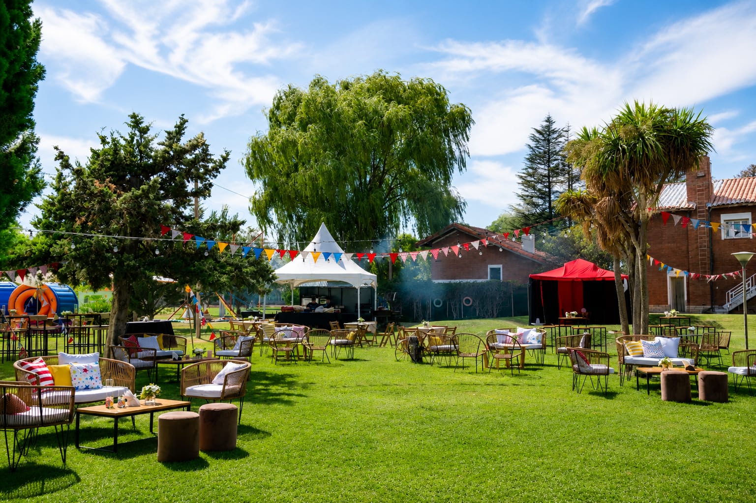 Jardín del predio de día con carpas, banderines de colores y livings montados para una celebración